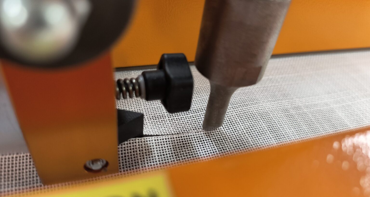 Ultrasonic cutting head trimming roller shade fabric in NYC workshop